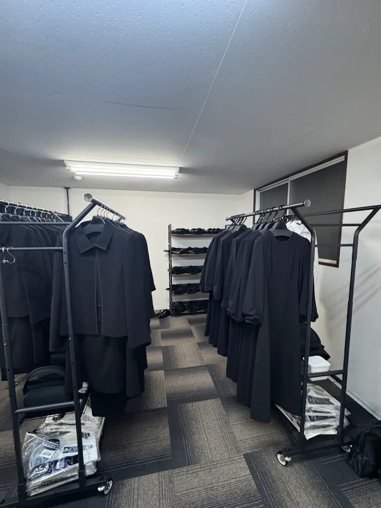 喪服レンタル24 堺三国ヶ丘店の無人店内。サイズ別の喪服が並ぶラック